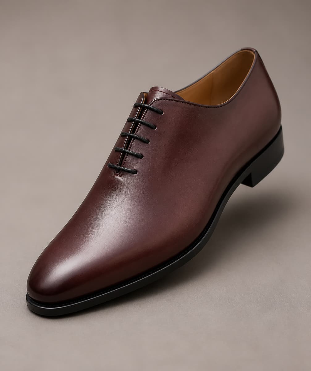 Richelieu homme bordeaux en cuir lisse avec laçage fermé, isolé sur fond gris chaud.
